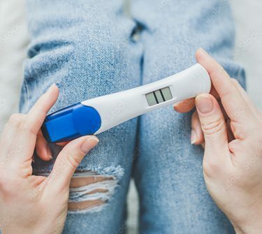 Person holding pregnancy test showing two lines