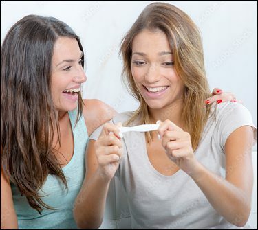 Two women smiling while looking at pregnancy test