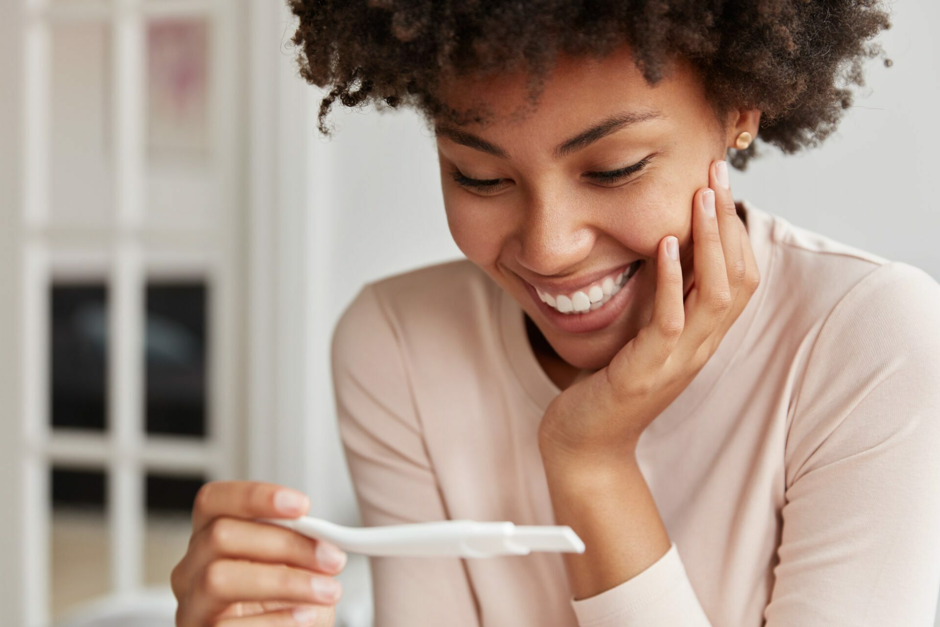 Woman smiling as she holds and looks at pregnancy test