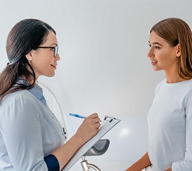 Healthcare professional taking notes while talking to woman