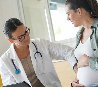 Healthcare professional touching pregnant woman's abdomen