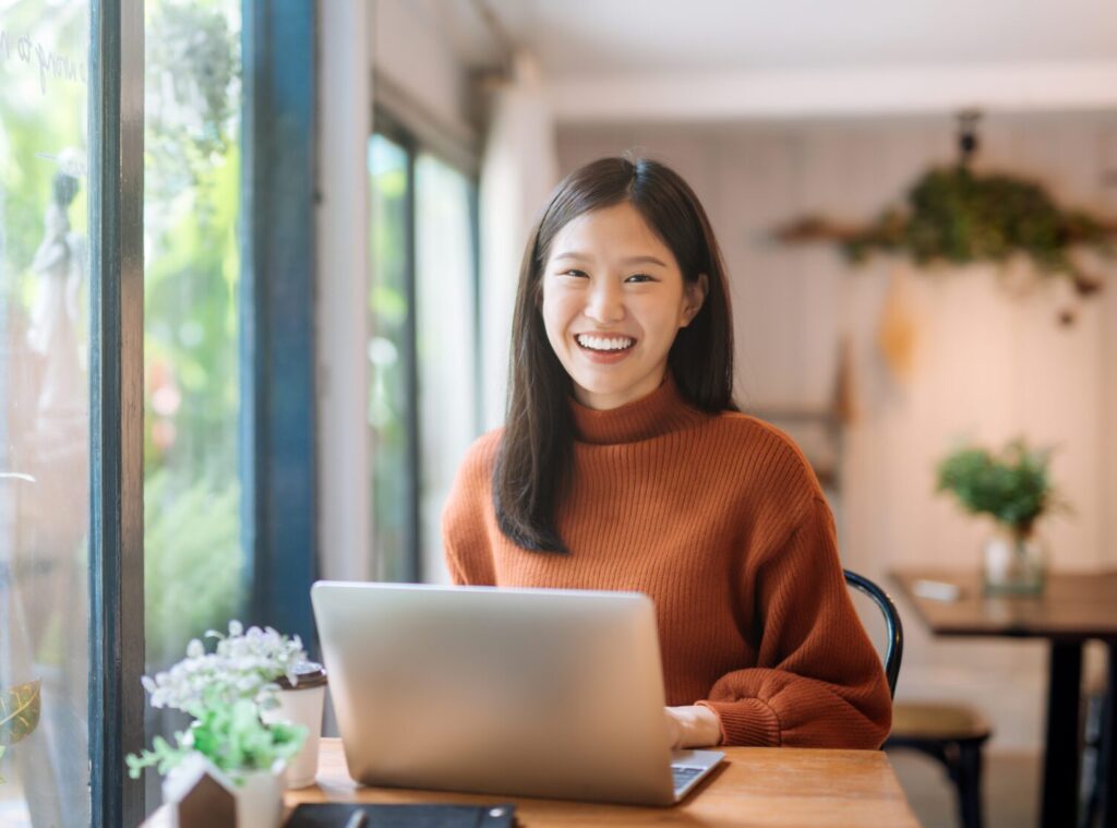 Happy young woman sitting inside using a laptop computer 