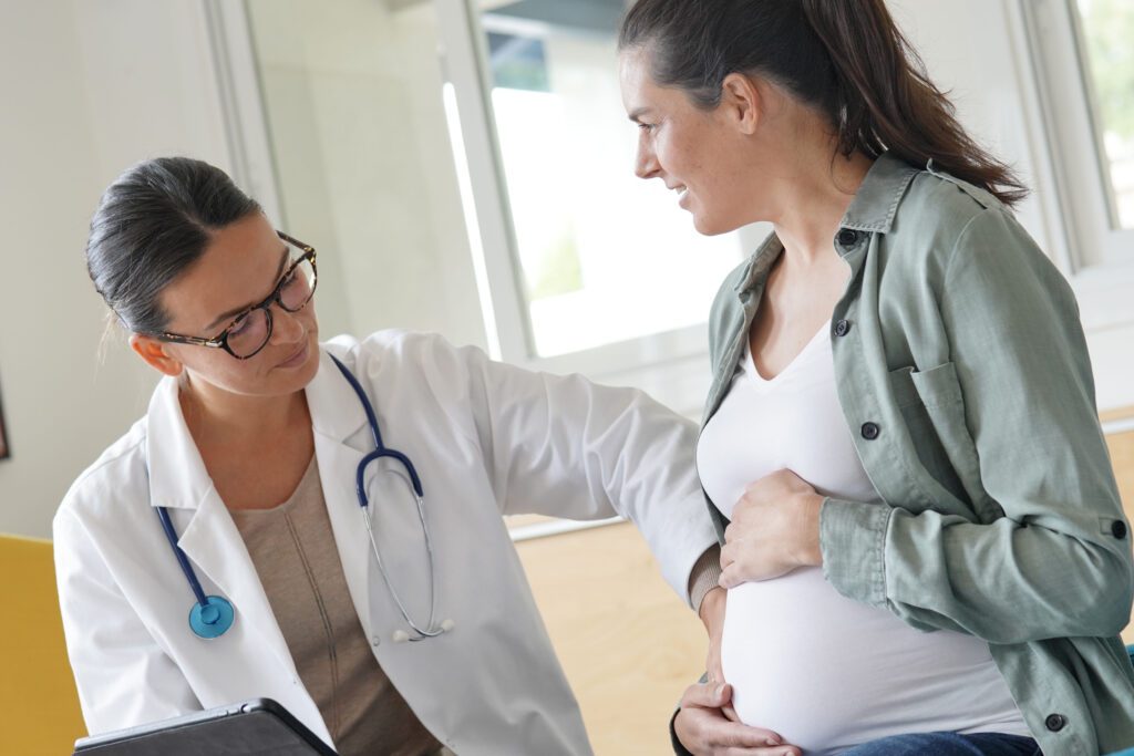 Healthcare professional touching pregnant woman's abdomen